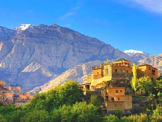 Kasbah du Toubkal perchée sur une colline sous un majestueux sommet