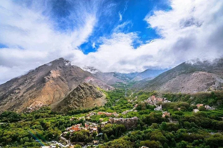 Vue panoramique sur une vallée verdoyante et un village niché entre de hautes montagnes