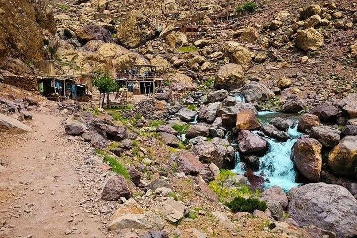 Rocky landscape with a small stream and rustic buildings in the background
